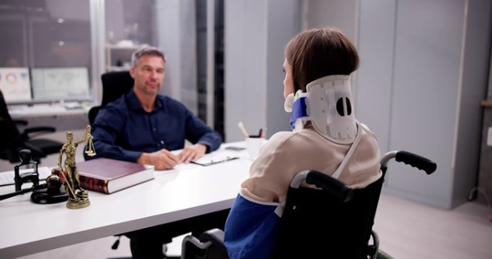 Personal injury attorney talking to person in wheelchair and neck brace