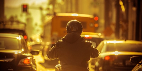 Motorcycle rider in between lanes of traffic.