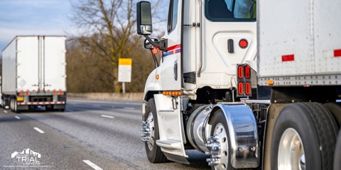 Two large semi-trucks on the road.