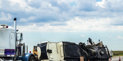 Fifth wheel RV overturned on highway with wench truck trying to get it off the road and two semis parked nearby and traffic cones keeping traffic away