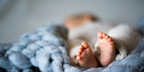 Closeup of baby feet on blue knit blanket