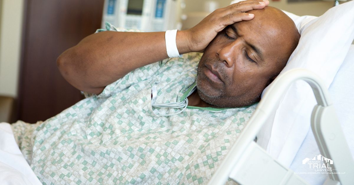 Man in a hospital bed with hand on his head.