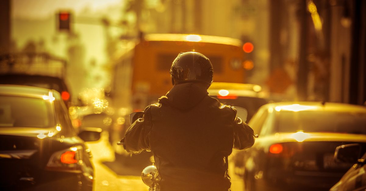Motorcycle rider in between lanes of traffic.