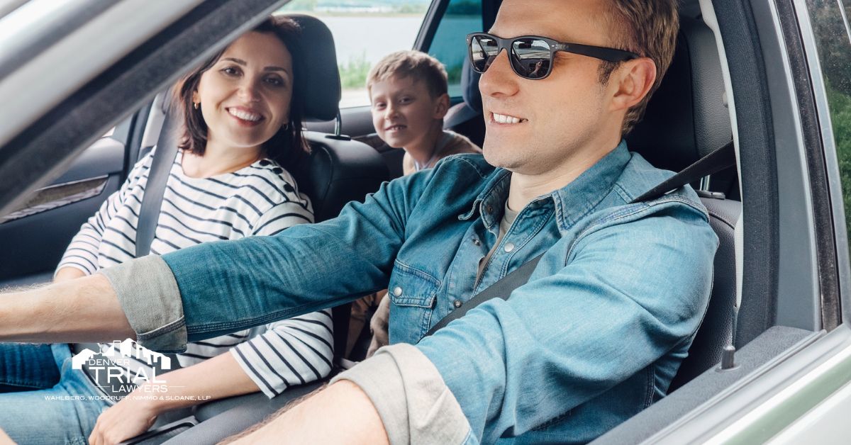 Father driving with mother in front passenger seat and young boy in the backseat.