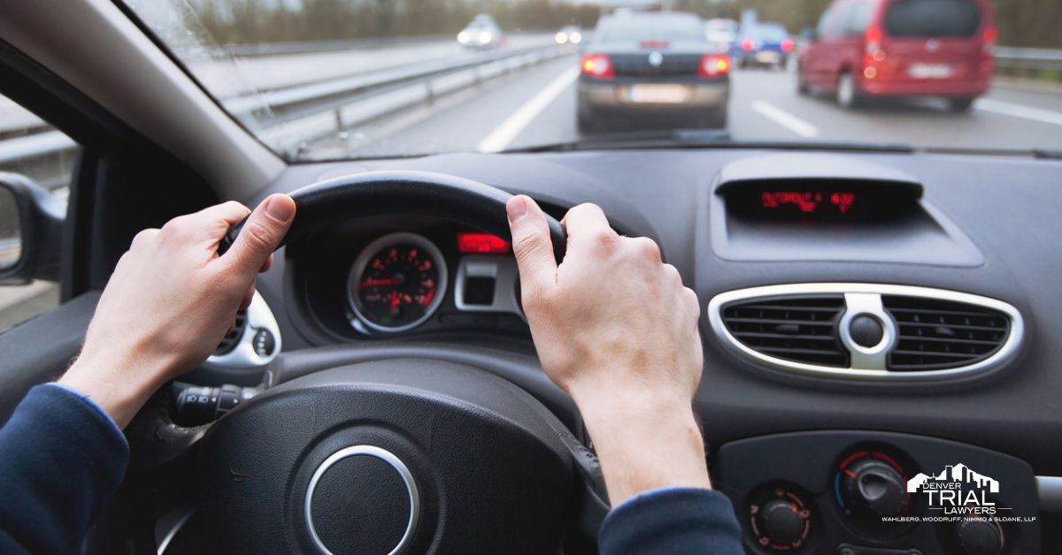 Driver in car with hands on steering wheel.