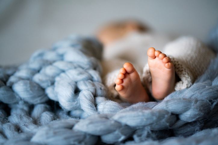 Closeup of baby feet on blue knit blanket